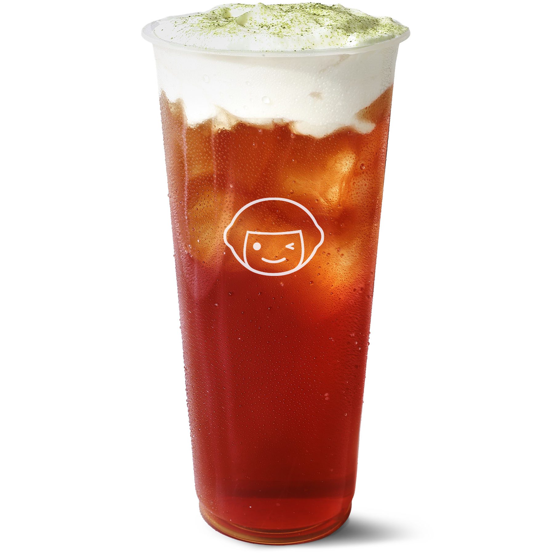 A tall, clear plastic cup filled with iced tea, topped with a layer of white foam and a sprinkle of green powder. The cup features a simple cartoon face logo on the front.