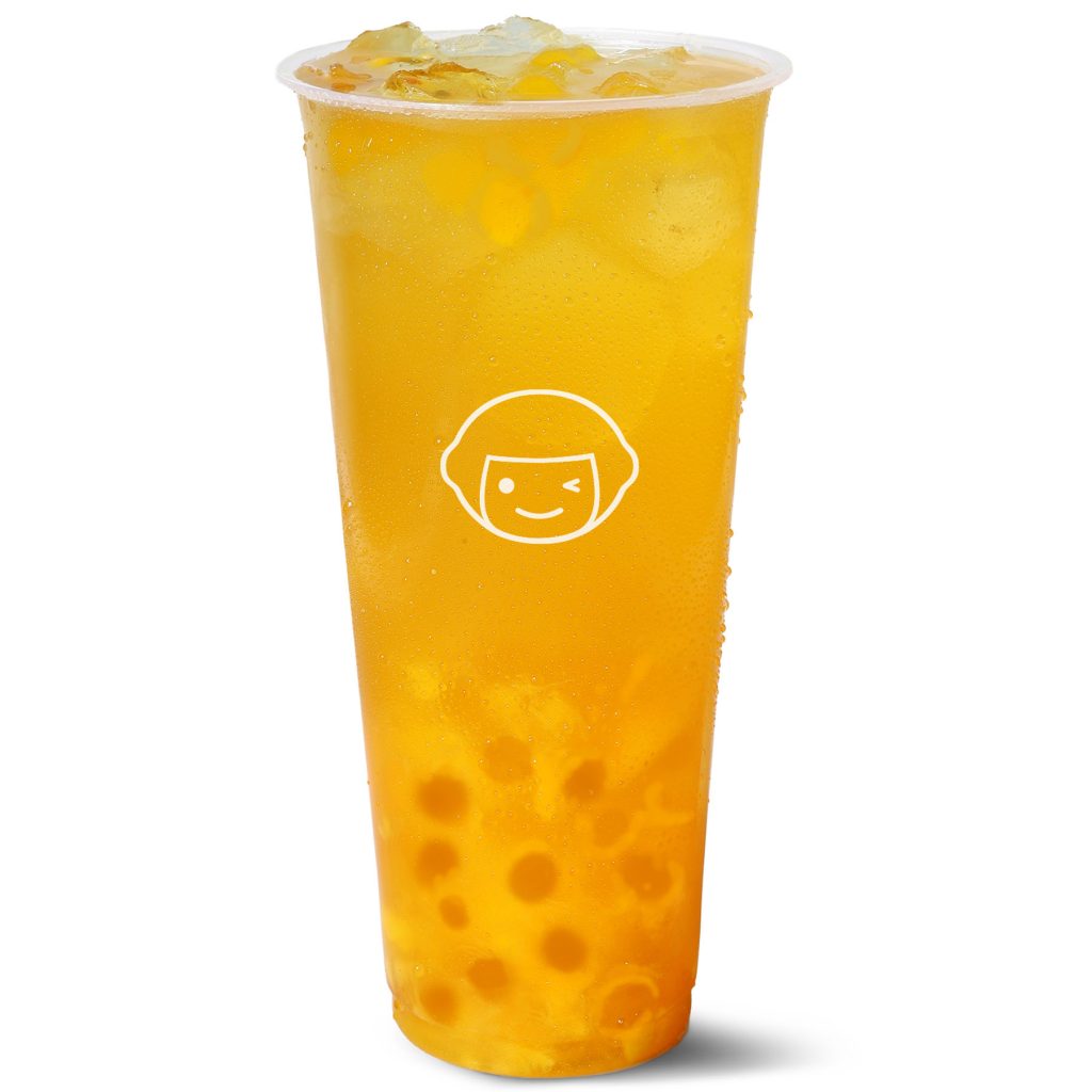 A tall, clear plastic cup filled with yellow iced tea and tapioca pearls, featuring a white cartoon face logo on the front of the cup.