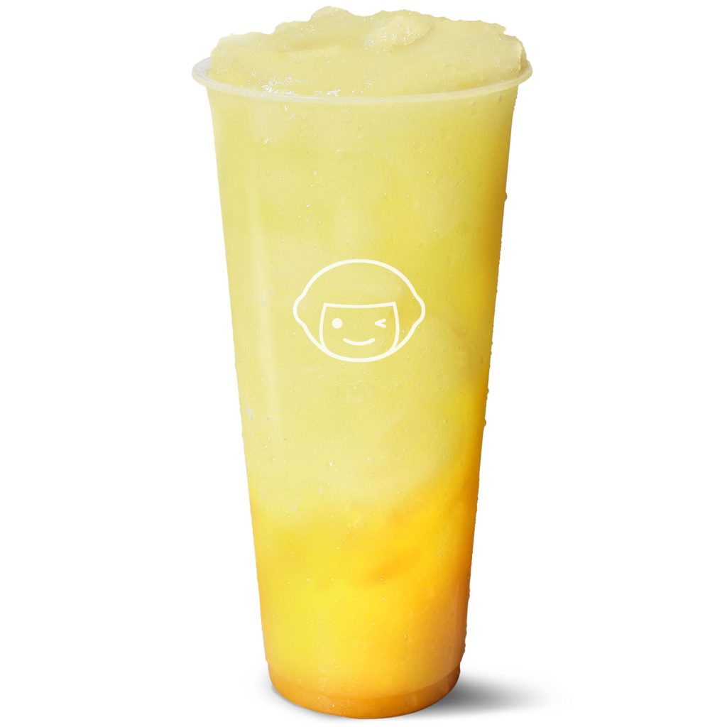 A clear plastic cup filled with a yellow and orange blended frozen drink, featuring a white smiling face logo on the front. The drink has a frothy, icy texture and appears cold with condensation on the cup.